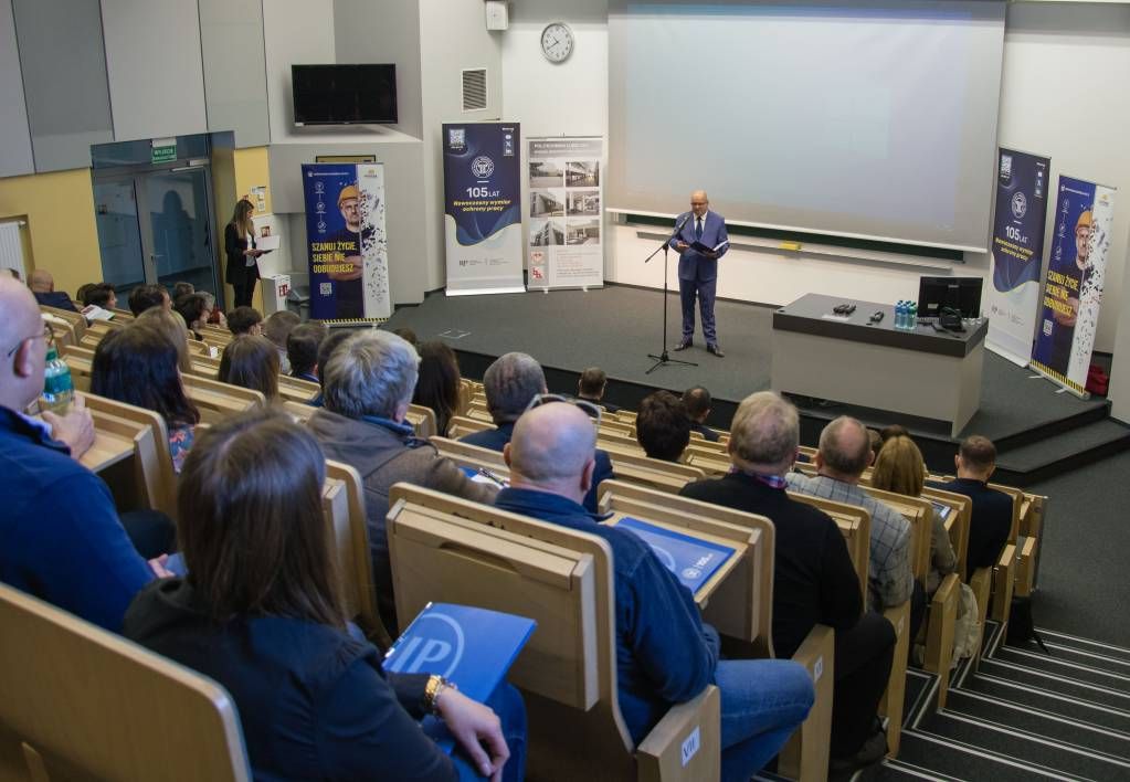 widok na salę konferencyjną z ludźmi i prelegentem 